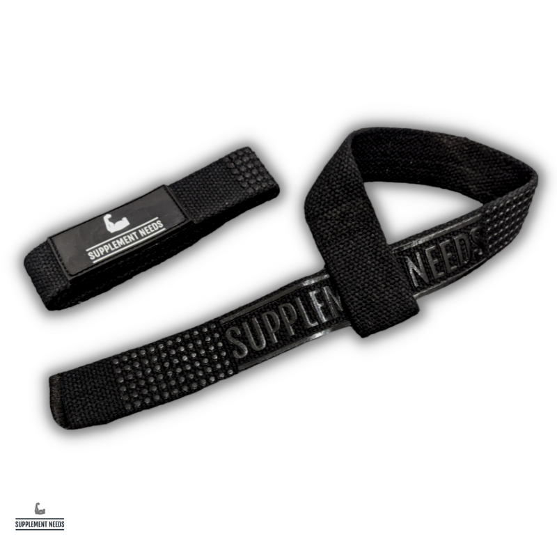 A pair of black lifting straps with the text 'Supplement Needs' printed across the grip area. The image shows the straps laid out with a focus on the texture and branding.