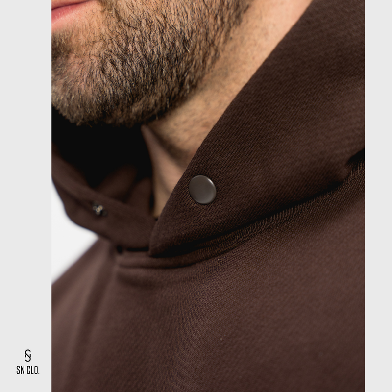 Close-up of a brown hoody with a button, featuring the brand 'SN CLO.'