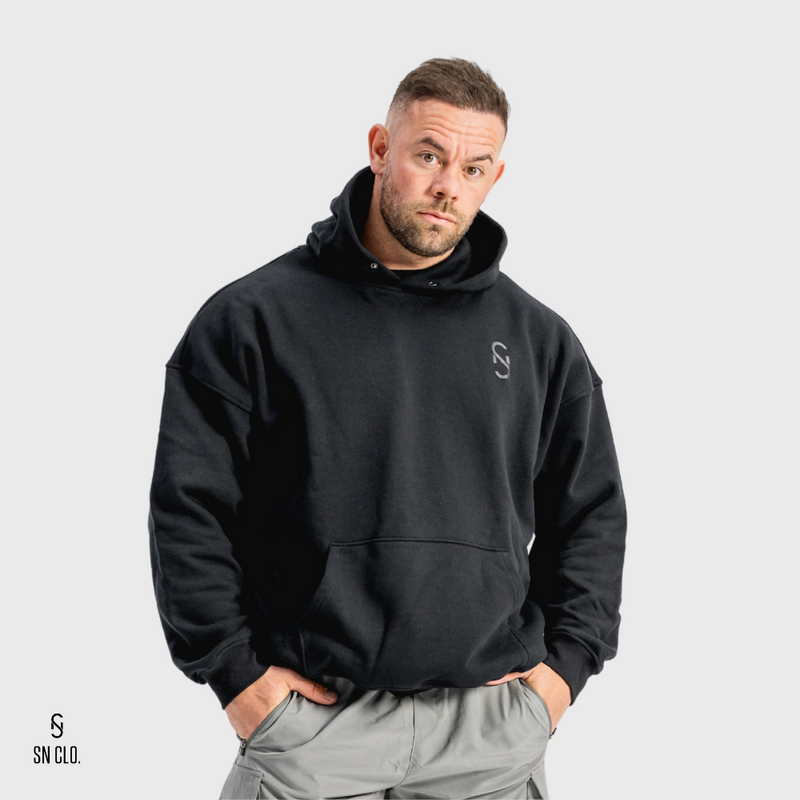 Man wearing a black hoody with an SN Clo logo on a grey background
